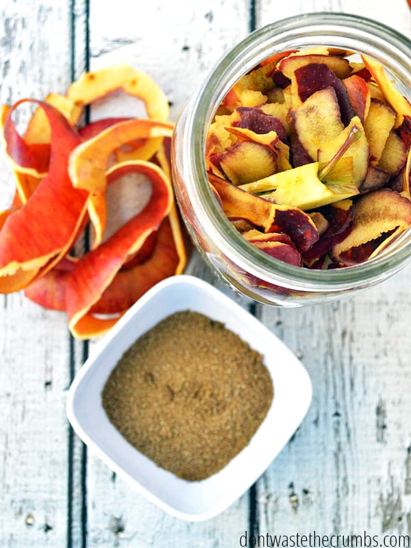 Peeled apples in a mason jar, apple peels, and a white bowl of sugar