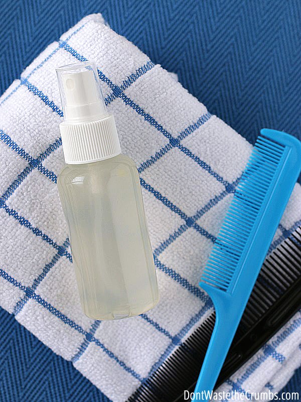 A plastic spray bottle of a natural hair conditioner and a plastic comb lie on a folded towel