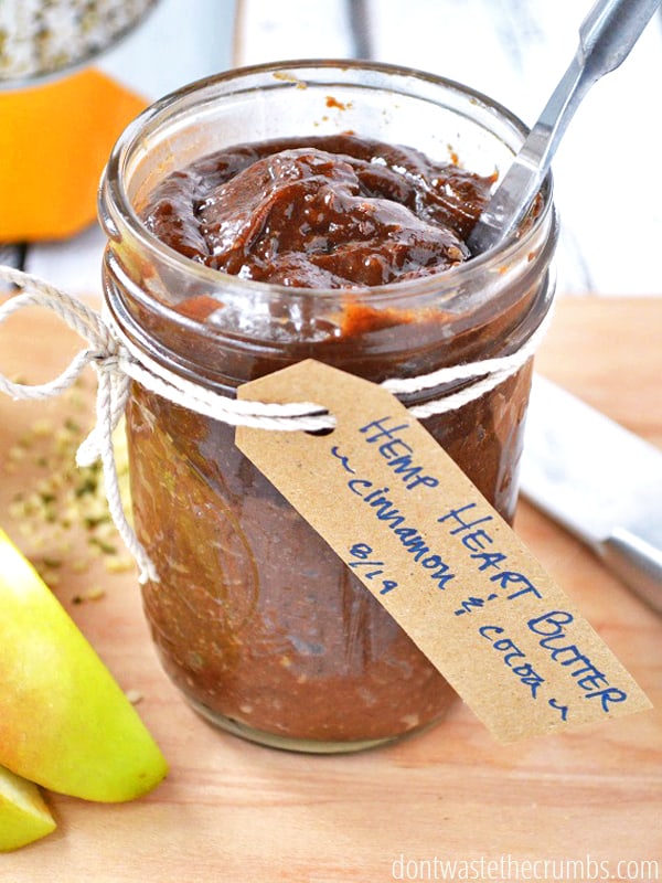 Homemade hemp heart butter with cinnamon and chocolate in a glass jar with a knife in the jar.