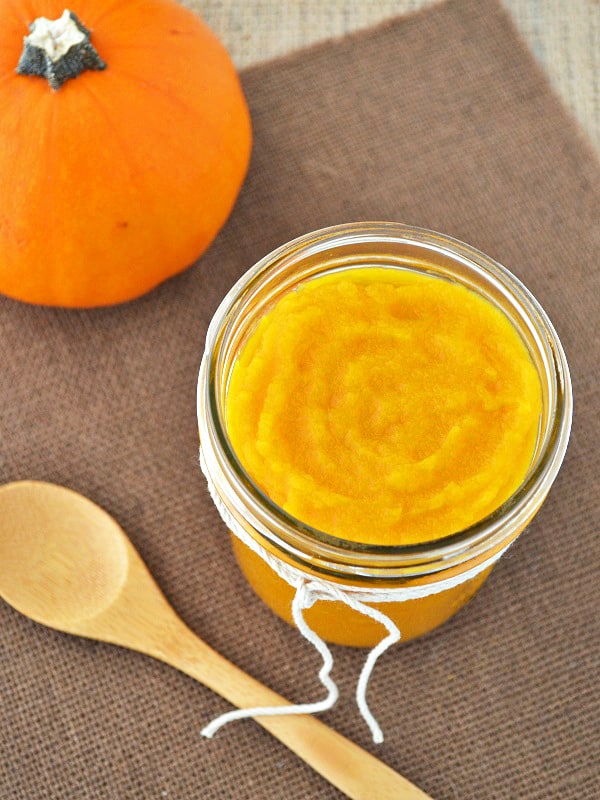 This homemade pumpkin puree can be used in your favorite recipes! You can make desserts with this or even baby food! This puree is in a jar from the top view with a wooden spoon beside it. Ready to be eaten!