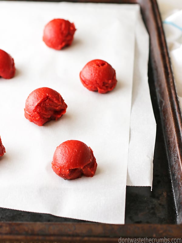 Small scoops of tomato paste on a parchment lined baking sheet