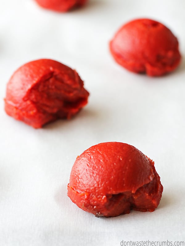 Small scoops of tomato paste on a parchment lined baking sheet