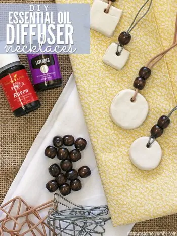 Bottles of Raven and Lavender essential oils, wooden necklace beads, bent paper clips and four completed necklaces. Text overlay DIY Essential Oil Diffuser Necklace