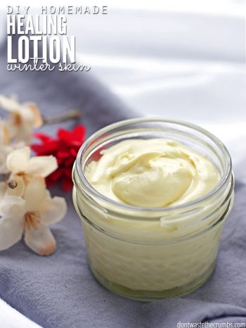 Small glass jar filled with a white lotion. White and red flowers in the background. Text overlay DIY Homemade Healing Lotion - Winter Skin.