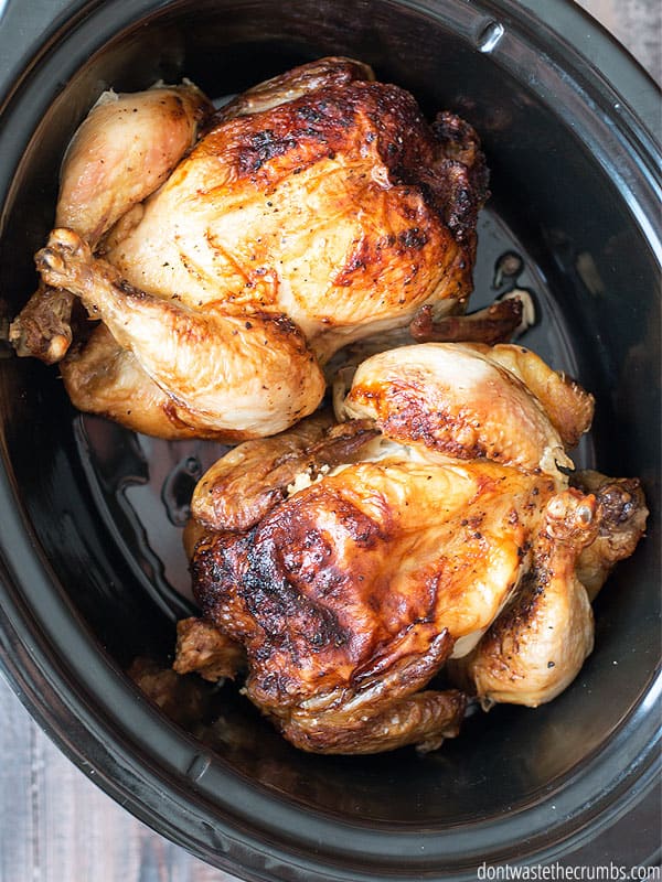 Two whole cooked chickens in a slow cooker.