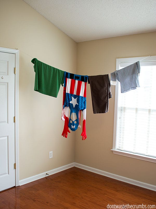 Two shirts, a part of pants and a costume hanging to dry on a homemade indoor clothesline.
