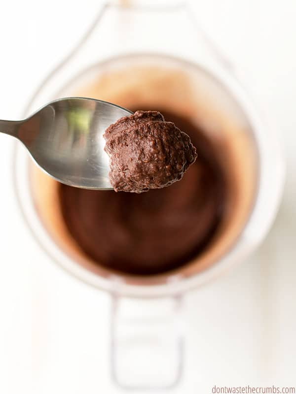 Spoonful of chocolate hummus with blender of chocolate hummus in the background.