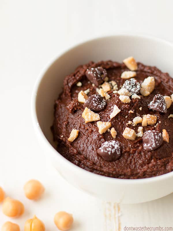 Bowl of chocolate hummus topped with chocolate chips, nuts and coconut.