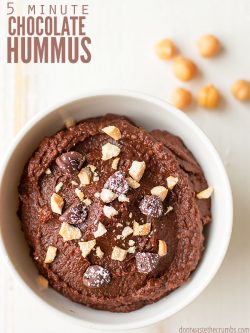 Bowl of chocolate hummus topped with chopped nuts, chocolate chips and flaked coconut with text overlay, "5 Minute Chocolate Hummus".