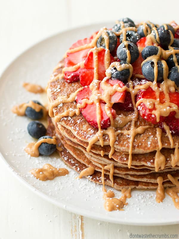 Protein pancakes with fresh strawberries and blueberries and drizzle of peanut butter and maple syrup.