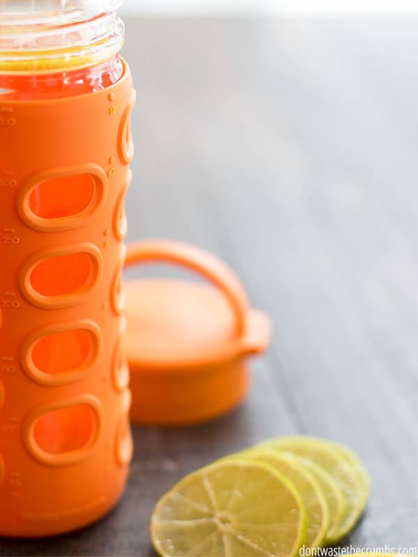 Orange water bottle and sliced lemons next to it