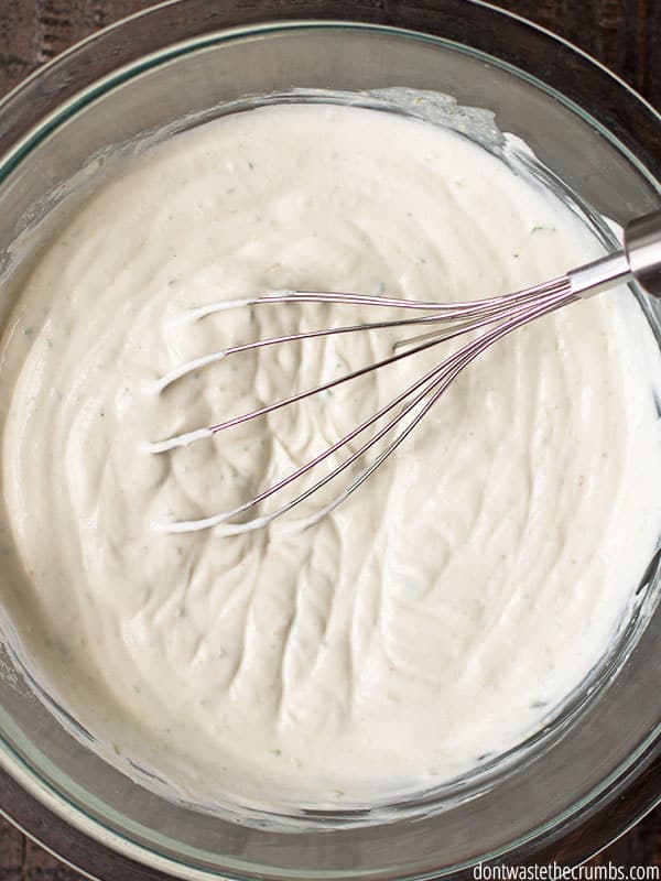 A whisk in a bowl of lime crema, already mixed together
