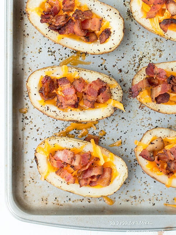 Potato skins on a baking sheet. There is bacon and cheese in the potato skin.