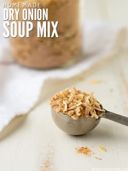 Measuring spoon filled with onion soup mix and a jar filled with the spice in the background. Text overlay says, "Homemade Dry Onion Soup Mix".