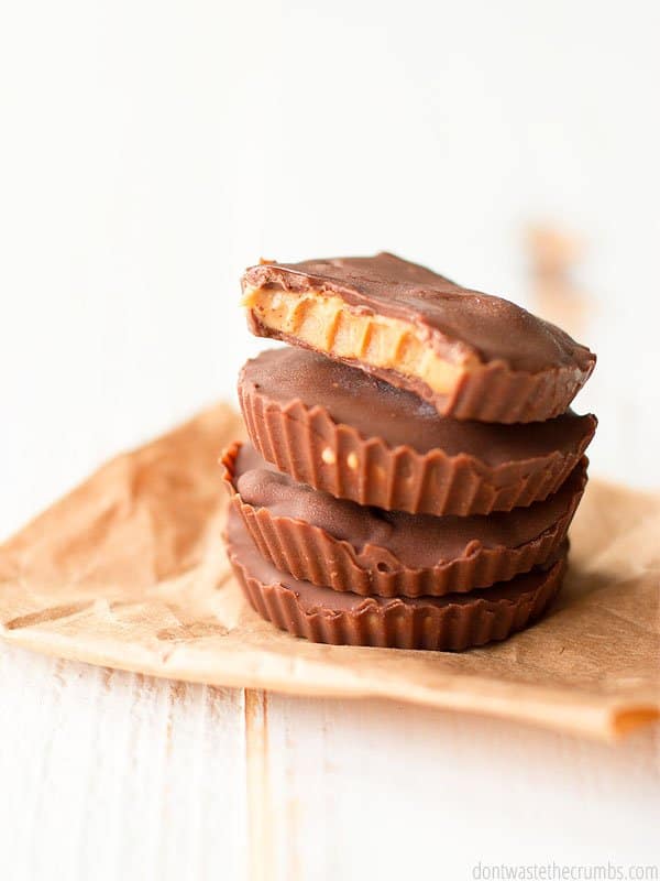 4 stacked pb cups on a brown napkin sat upon a wooden grained table. The top treat has a bite taken out of it.