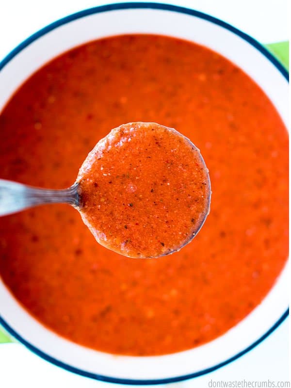 Roasted red pepper tomato soup in a large pot. Up close view of a big spoonful.