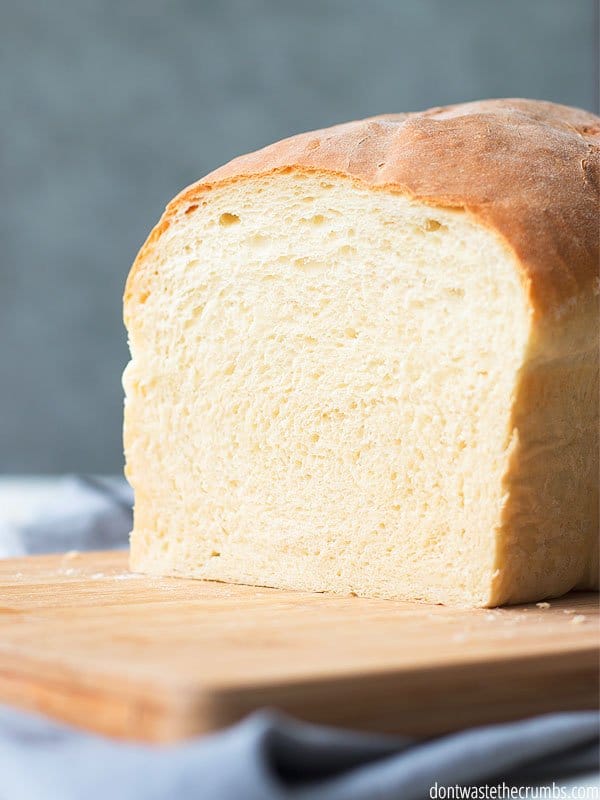 Homemade sandwich bread cut in half on a cutting board.