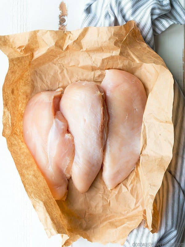 Raw chicken breasts in parchment paper.