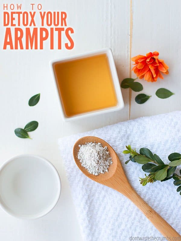 Ingredients for armpit detox separated in different bowls and a wood spoon. Orange flower and green leaves sprinkled on the table. Text overlay reads, "How To Detox Your Armpits".