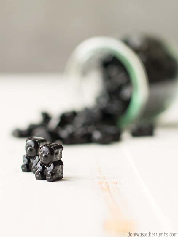 A glass jar with charcoal gummies spilling out on a table and an up close view of the gummies.