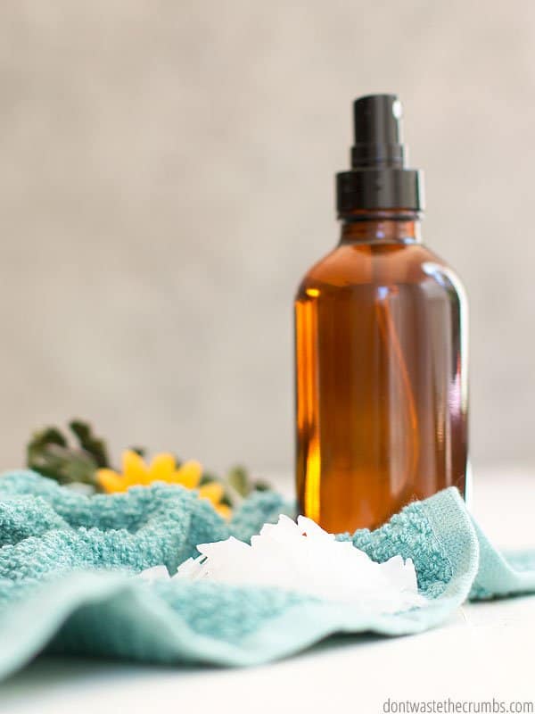 Glass amber spray bottle and a pile of magnesium chloride flakes on a towel.