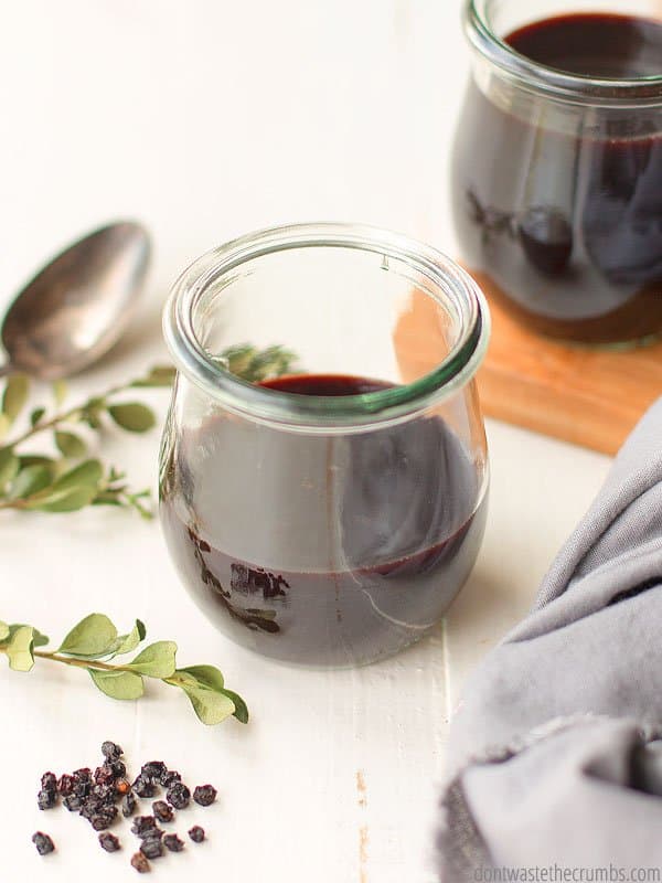 Small glass cup of elderberry syrup