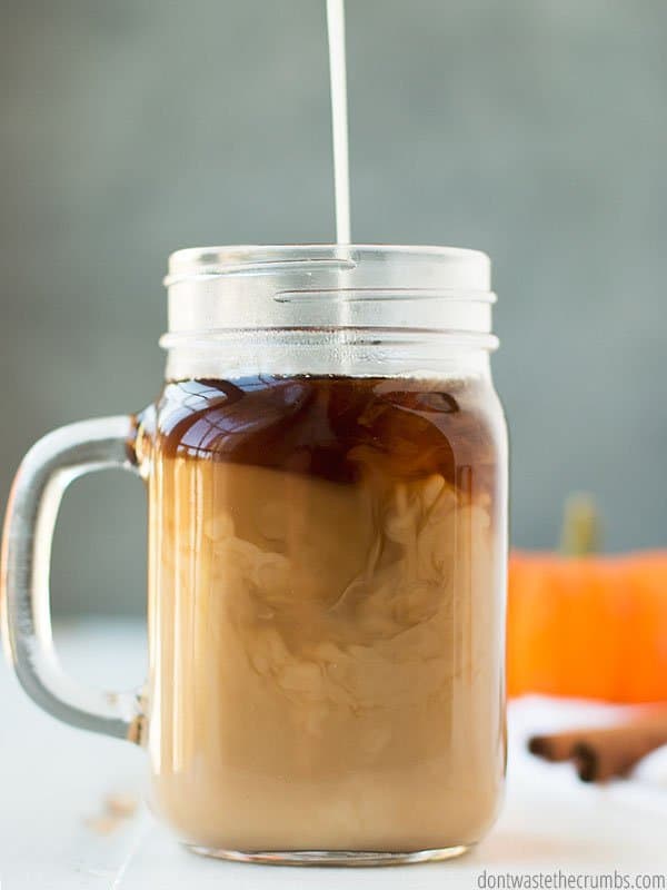 Pumpkin spice coffee creamer is being poured into a bug glass of coffee. Made with homemade pumpkin pie spice, and much healthier than the powder!