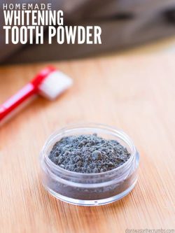 Small jar of tooth whitening powder with a toothbrush. Text overlay says, "Homemade Whitening Tooth Powder".