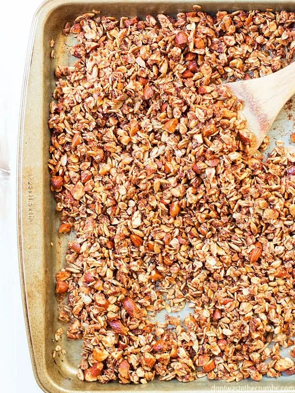 Cinnamon granola mixture is being scooped onto a baking sheet.