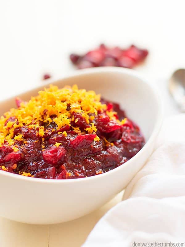 Homemade cranberry sauce with orange zest in a white bowl.