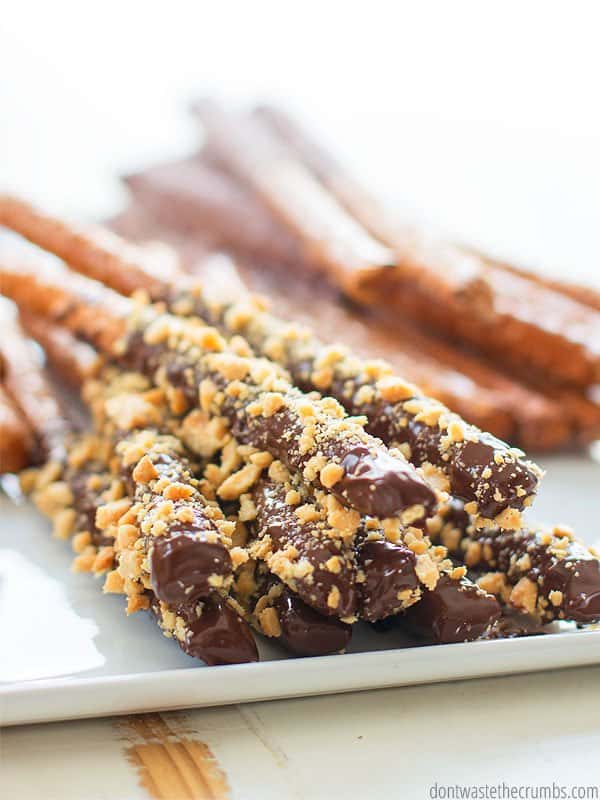 A stack of dark chocolate dipped pretzels with peanut topping. 