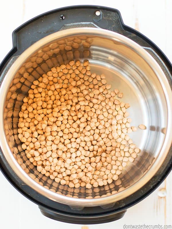 There are raw garbanzo beans in the pot of an Instant pot. This is the first step in making Instant Pot beans.