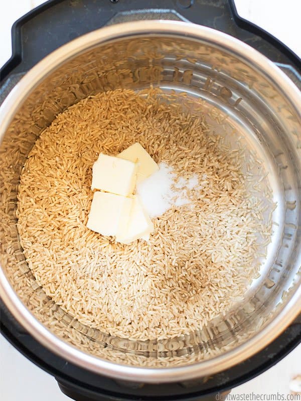 This is an overview of an Instant Pot with brown rice and water and butter in the pot.