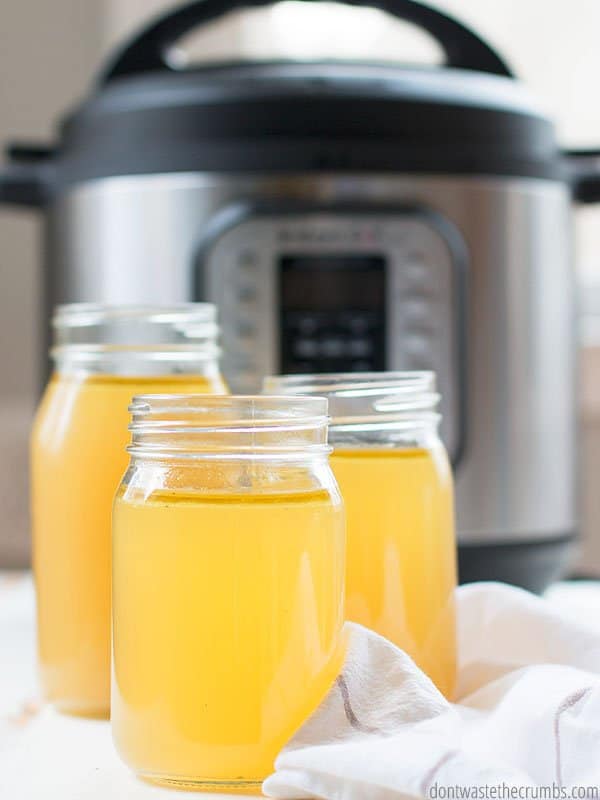 Learn how to make chicken stock in your Instant Pot pressure cooker with this simple tutorial. An Instant Pot is in the background of three full mason jars of chicken stock. 