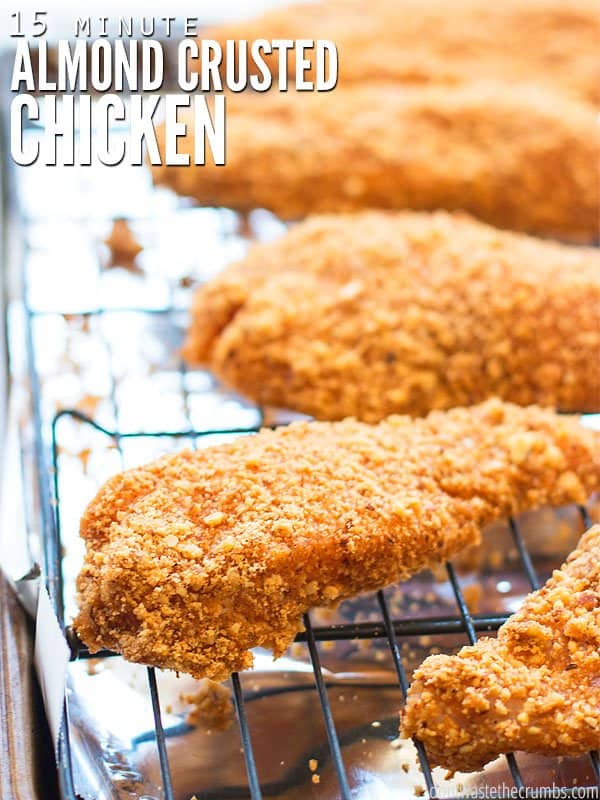 Almond crusted chicken on a wire rack lined with aluminum foil on a baking sheet. Text overlay reads, "15 Minute Almond Crusted Chicken".