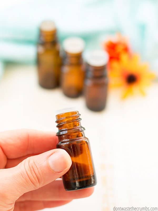 Up close view of a hand holding an amber glass essential oil bottle.