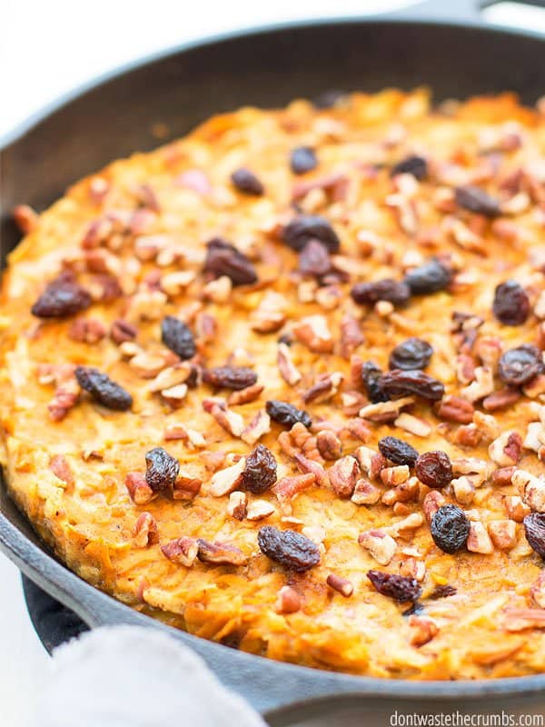 A freshly baked sweet potato casserole in a cast iron skillet with toasted nuts and raisins on top!