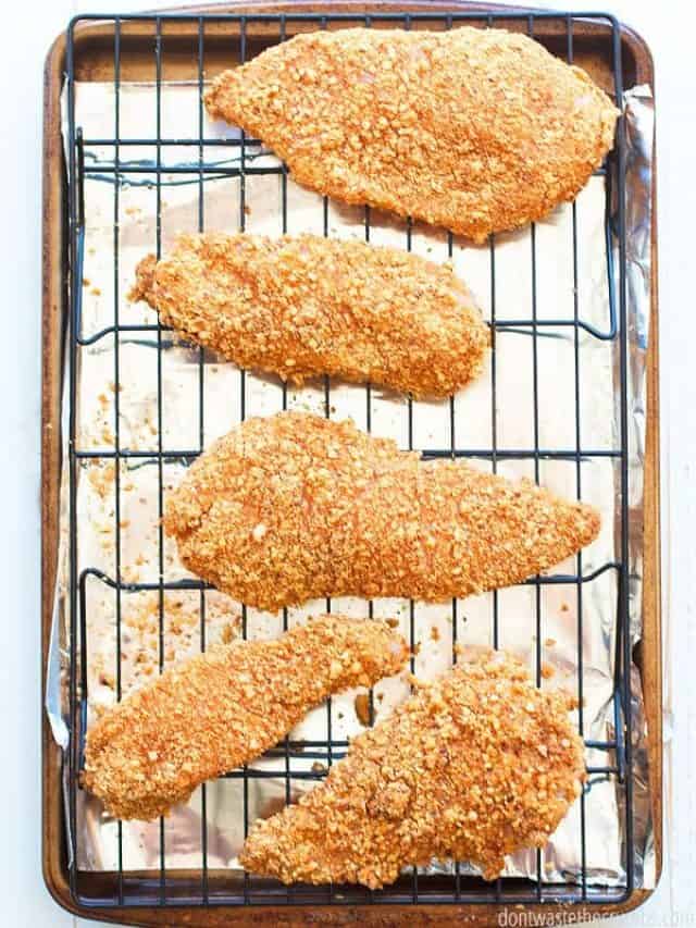 cropped-Almond-Crusted-Chicken-2.jpg Five almond-crusted chicken on a cooking rack on a aluminum foil lined baking sheet.