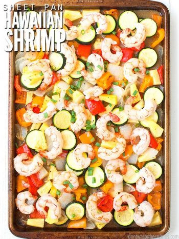 Stone baking sheet filled with peeled shrimp, browned red and orange peppers, white and green onions and pineapple chunks. Text overlay Sweet Pan Hawaiian Shrimp.