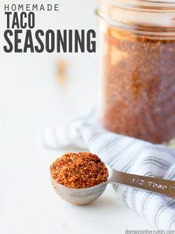 ½ Teaspoon measuring spoon with a heaping scoop of red and orange taco seasoning. Mason jar full of same colorful seasoning in the background. Text overlay Homemade Taco Seasoning.
