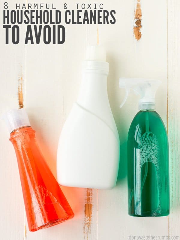 Three plastic dispenser bottles, one clear with red liquid, one clear with green liquid and one a solid white. All on a distressed wood table. Text overlay 8 Harmful & Toxic Household Cleaners to Avoid.