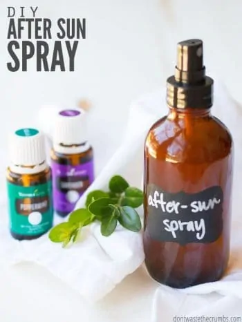 A brown spray bottle with After-Sun Spray written in white chalk pen on a black label. Peppermint and Lavender essential oil bottles in the background. Text overlay DIY After Sun Spray.