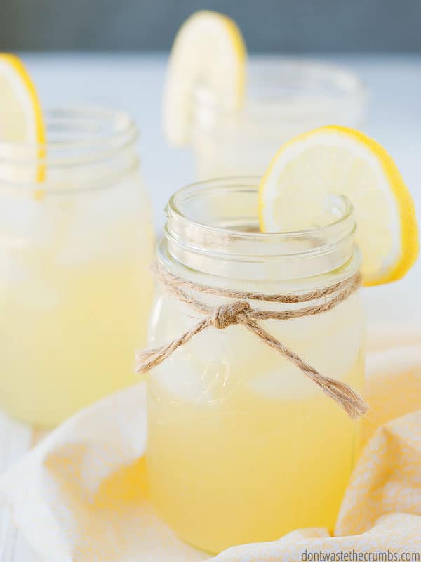 Homemade lemonade in two mason jars with lemon wedges on both rims