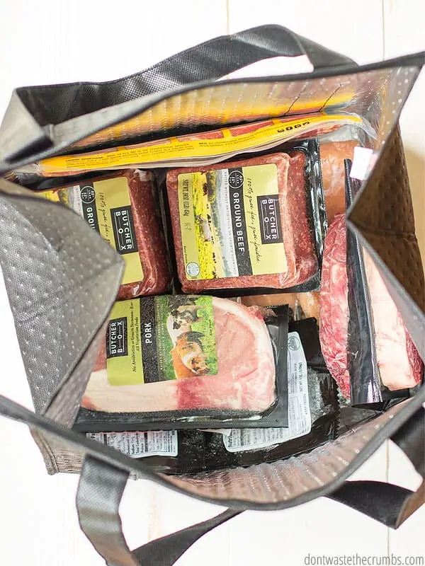 Various packages of frozen meats and chicken, all in Butcher Box packaging, in an insulated tote. 