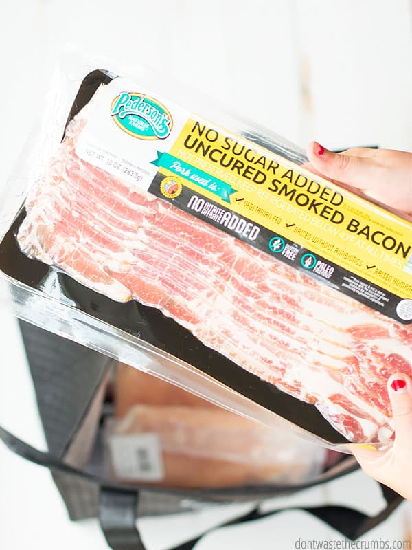 Hands holding a package of bacon shown over white background.