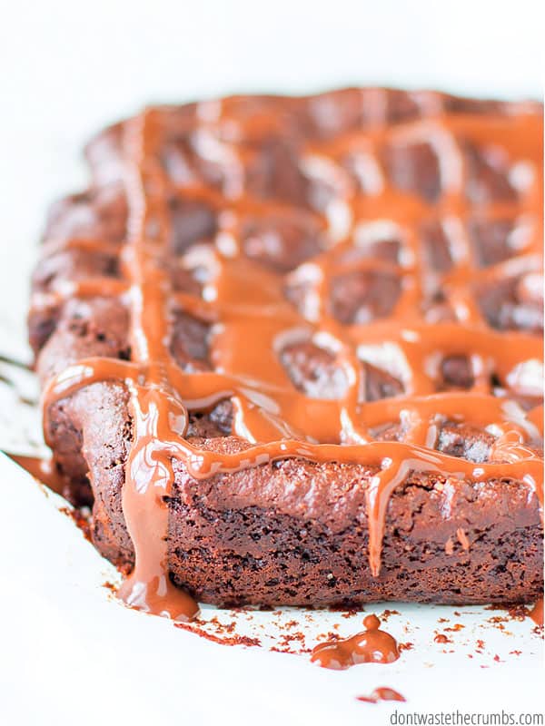 Huge brownie with chocolate sauce drizzled in a criss-cross pattern. Text overlay One Bowl Fudgy Paleo Brownies.