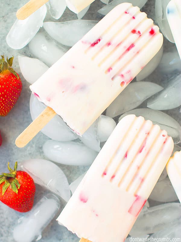 Two strawberry yogurt popsicles on ice.