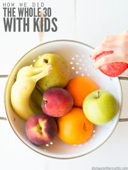 Assorted ripe fruit in a white colander on a vintage white wooden table. Text overlay How We Did the Whole 30 with kids.