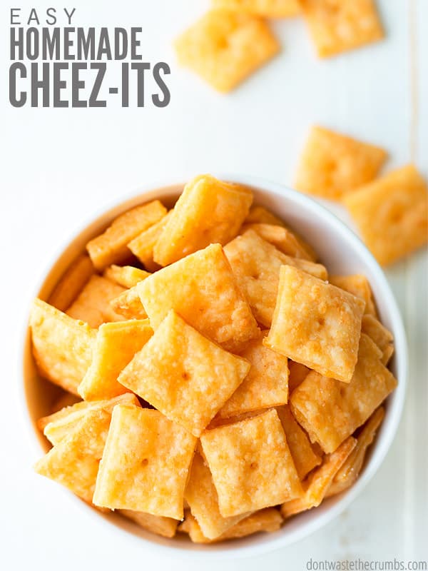 Round white bowl overflowing with Cheez-It like crackers. Text overlay Easy Homemade Cheez-Its.