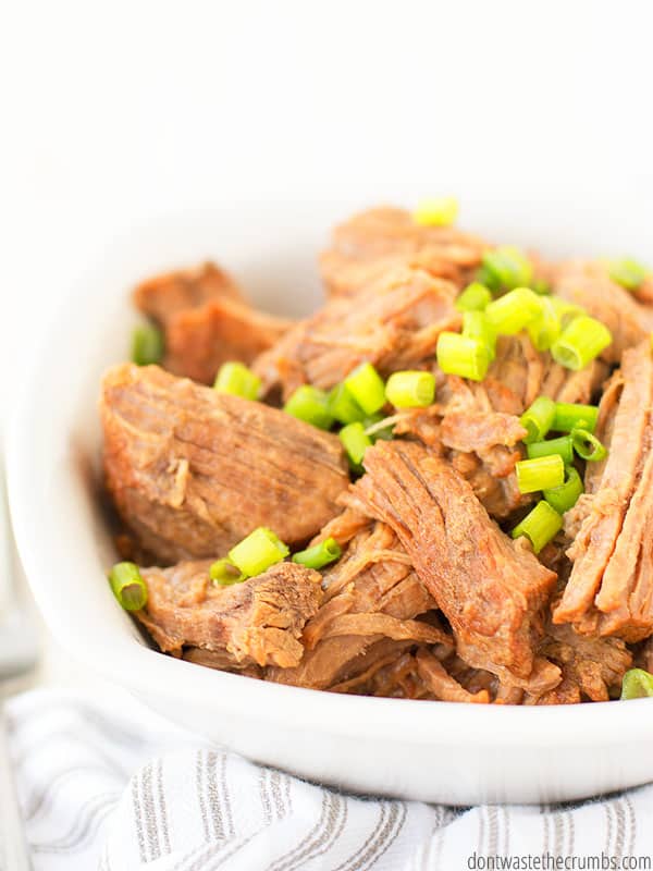 This Korean beef is paleo, keto, and whole30 friendly. The image shows cooked beef topped with chives set inside a white bowl.